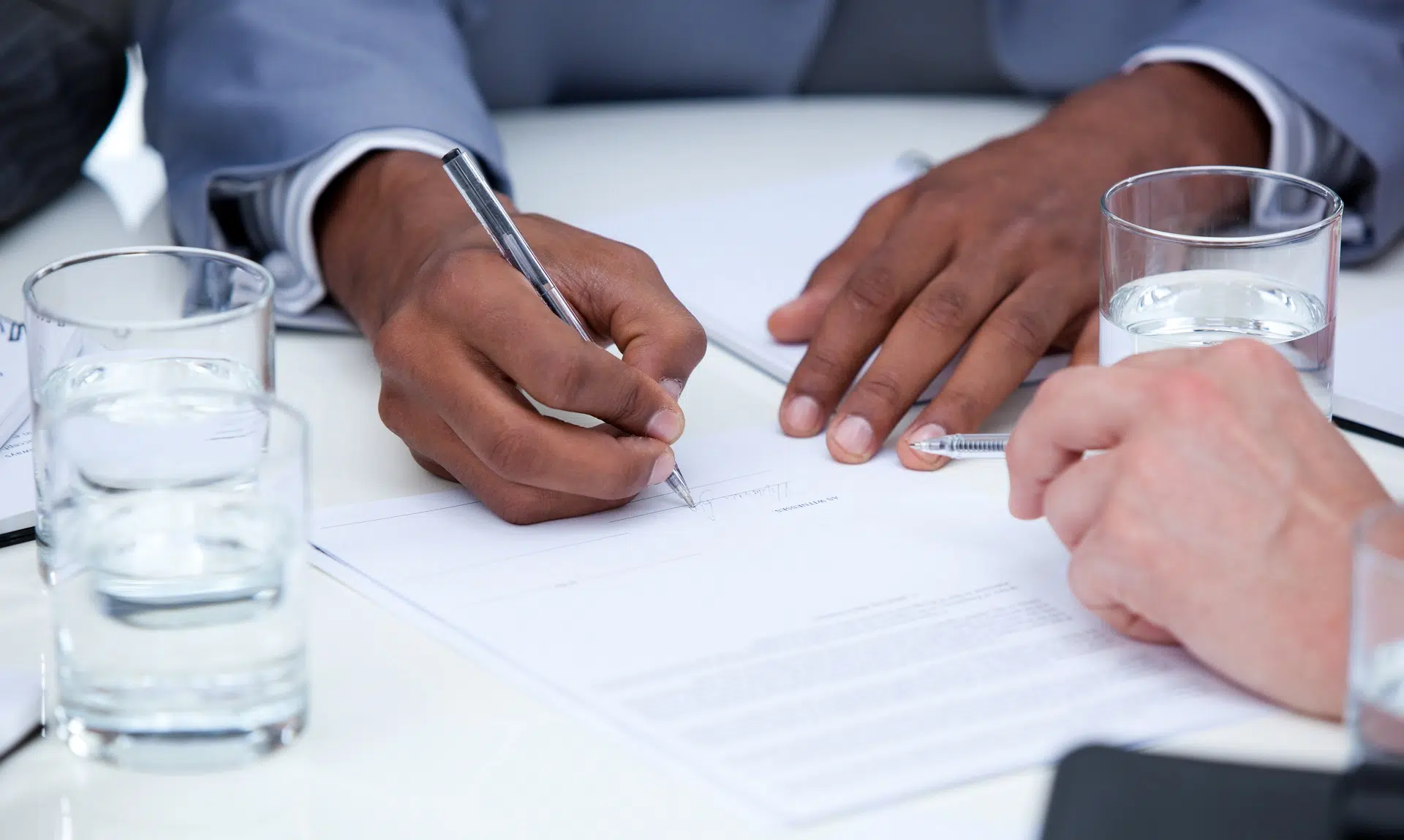 Two individuals signing documents | International Divorce Attorney | The Hemmat Law Group