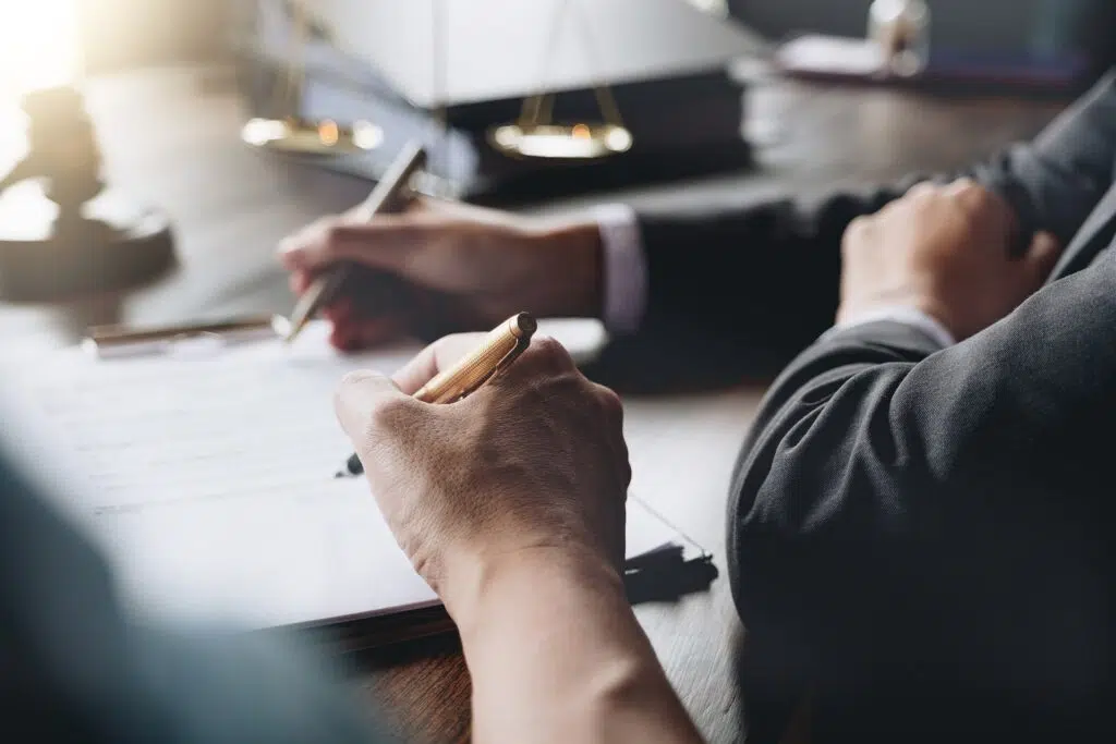 People signing legal documents at a table | Domestic Violence Law | The Hemmat Law Group