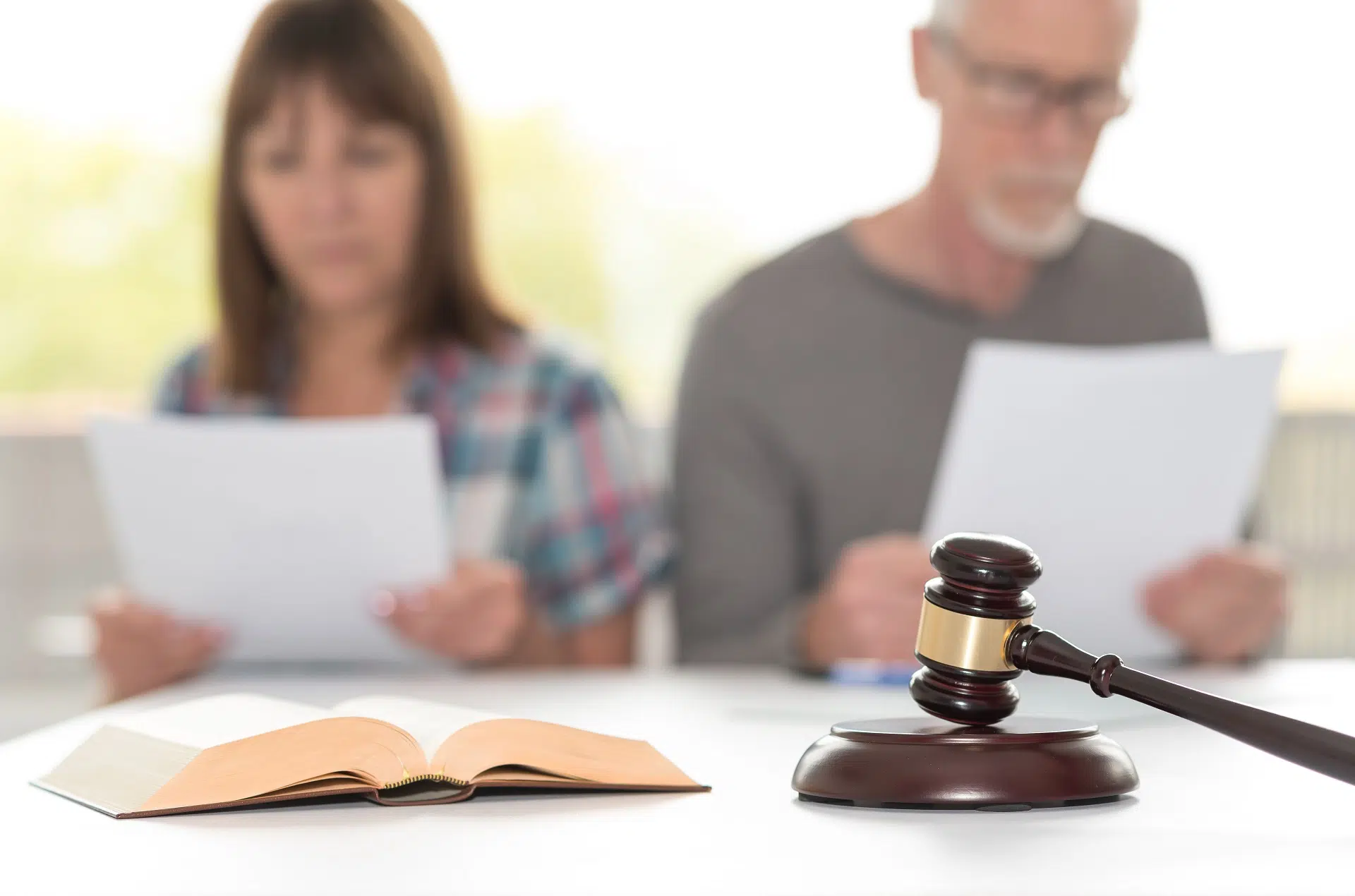 A gavel rests near an open book as two read documents | Divorce Lawyer | The Hemmat Law Group