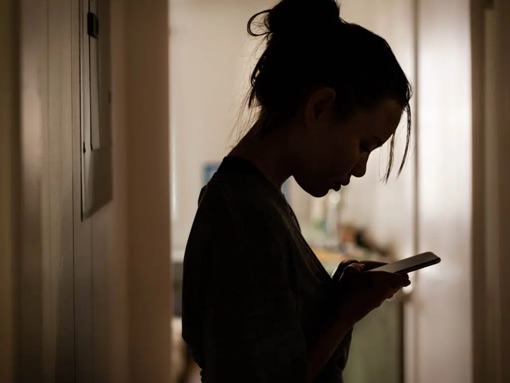 A Woman Scrolling Through Her Smartphone | Domestic Violence Lawyer | The Hemmat Law Group