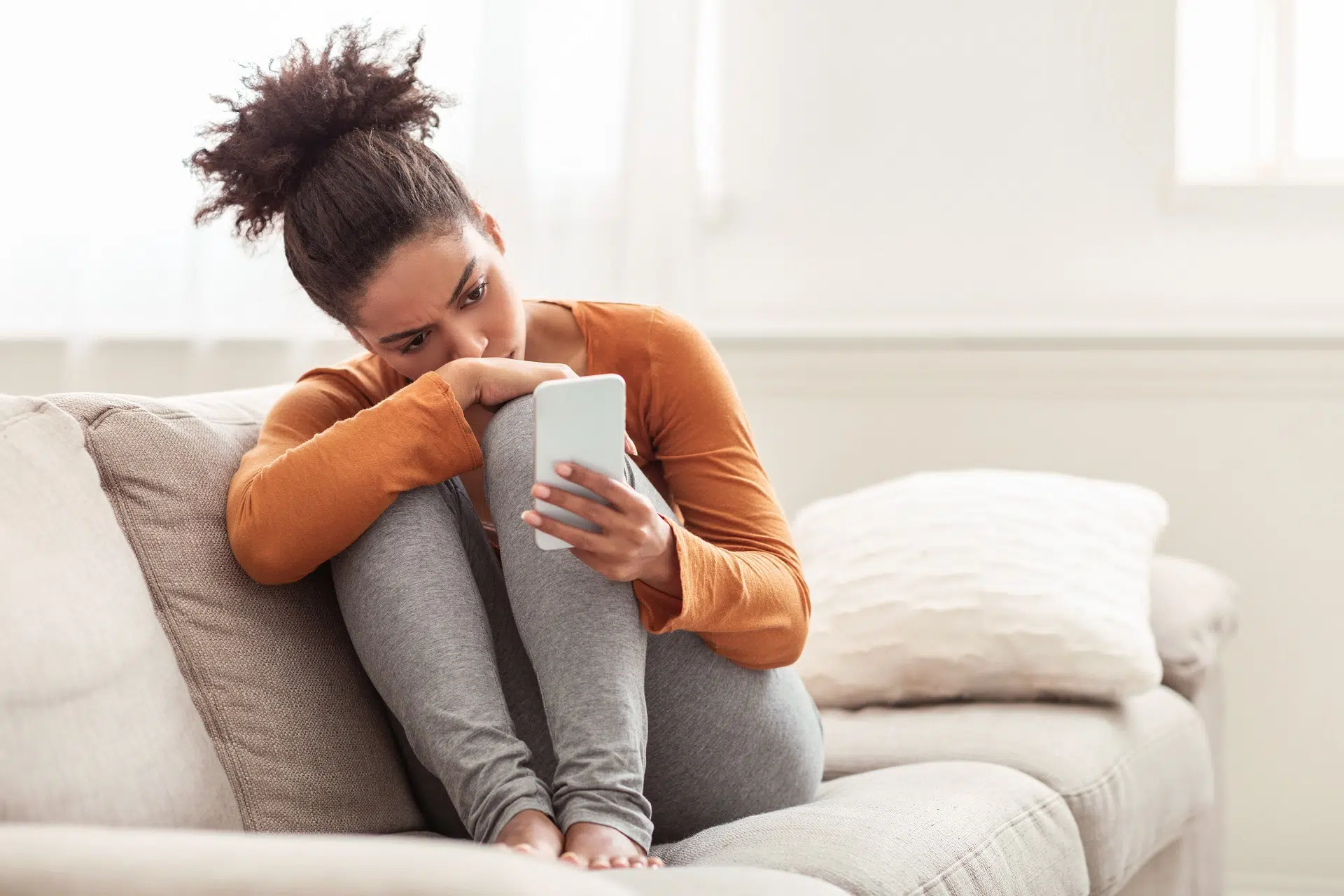 Woman looking at phone on couch  | Domestic Violence Law | The Hemmat Law Group