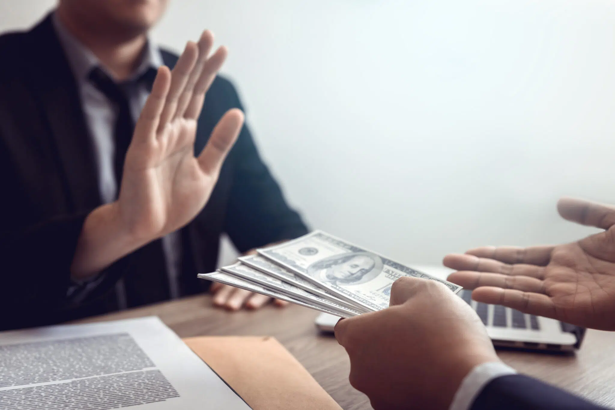 A businessman in a suit gestures to decline money | family law attorney | The Hemmat Law Group