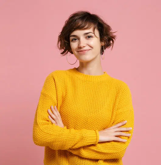 Smiling woman in a yellow sweater against a pink background | Family Lawyer | The Hemmat Law Group