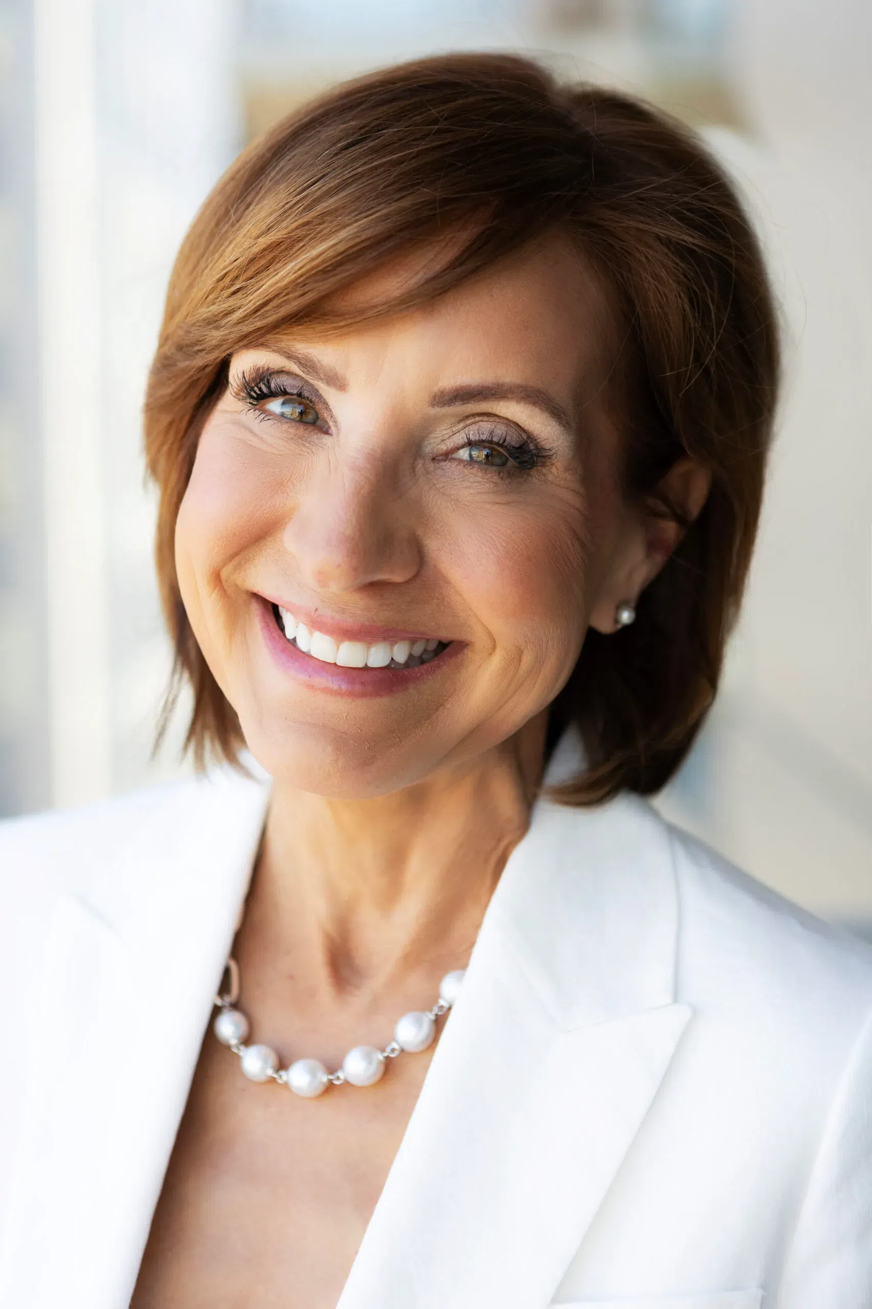 Smiling woman with short brown hair, wearing a white blazer | Family Lawyer | The Hemmat Law Group