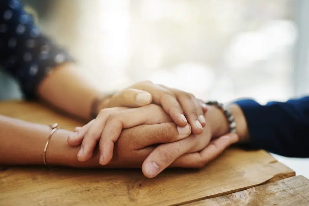 Two people holding hands on a wooden surface | mediation lawyer | The Hemmat Law Group