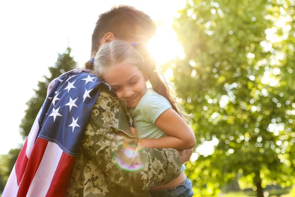 Soldier hugging child with American flag | Divorce Lawyer Seattle | The Hemmat Law Group