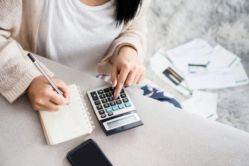 A woman calculates expenses, notes, and papers around her | Divorce Lawyer | The Hemmat Law Group