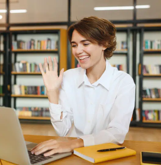 miling person waving during a video call on a laptop | mediation services | The Hemmat Law Group