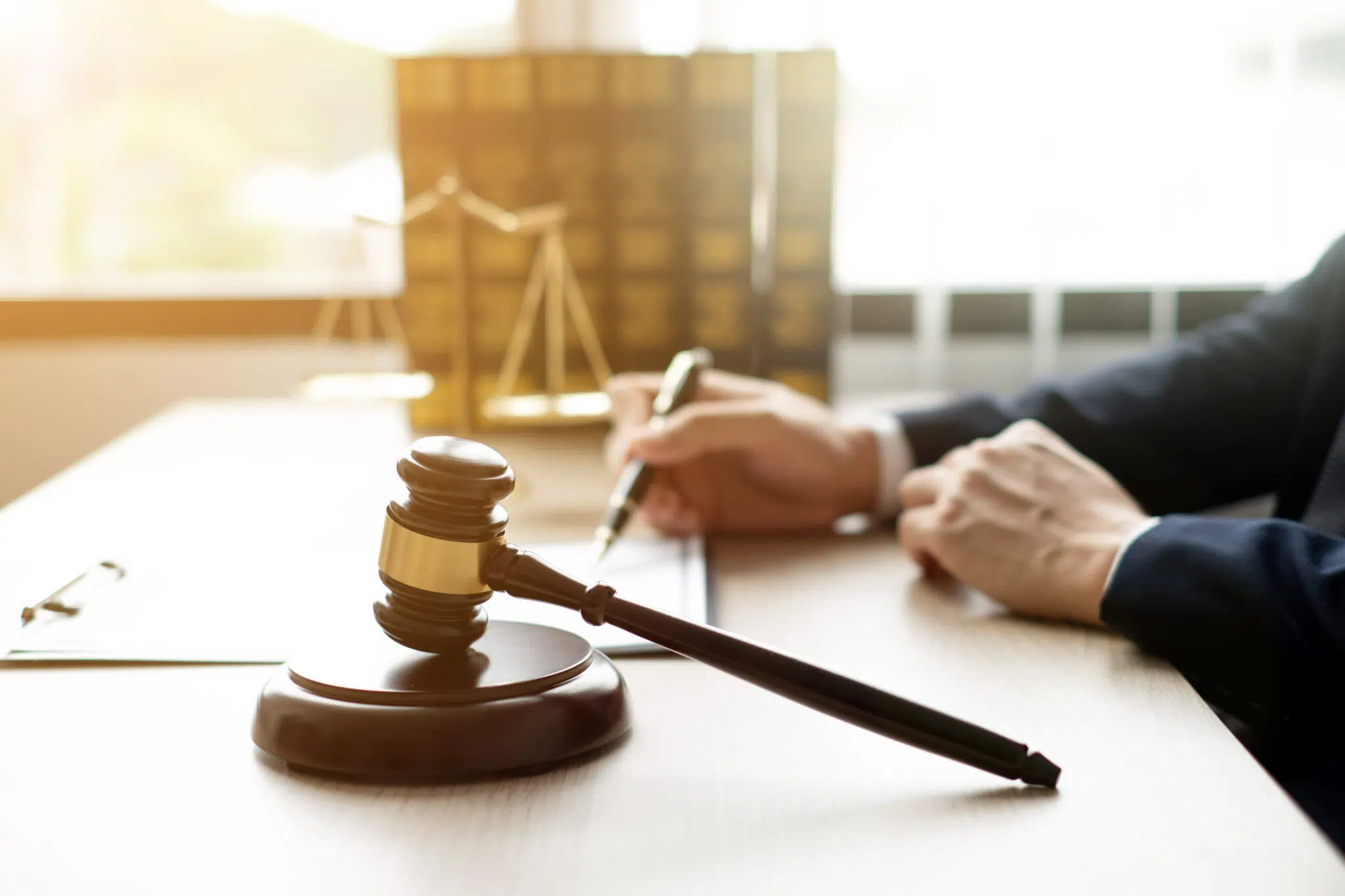 Gavel on a desk with a person writing in the background | mediation services | The Hemmat Law Group
