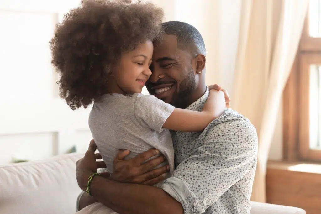 Man hugs a curly-haired child in a warm, cozy space | Child Custody Lawyer | The Hemmat Law Group