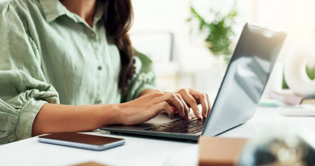 Person in a green shirt types on a laptop | Child Support Agreement  | The Hemmat Law Group
