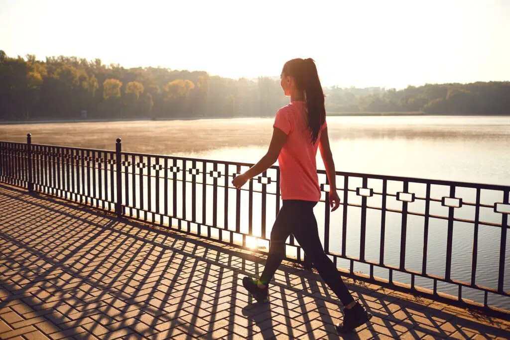Woman in a pink top walks along a lakeside path | Divorce Lawyer Seattle | The Hemmat Law Group