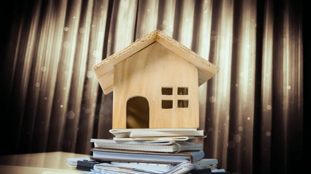 Wooden house model sits atop a stack of notebooks | High Asset Divorce Lawyer | The Hemmat Law Group