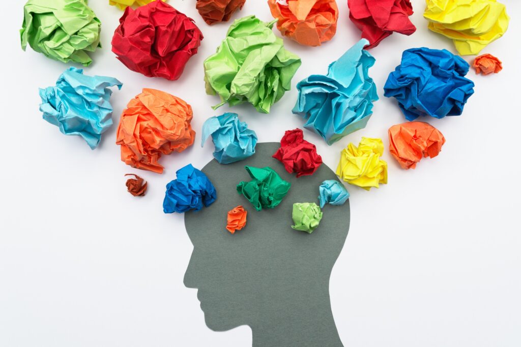 Balls of colored paper represent thoughts coming out of a paper silhouette of a person's head.