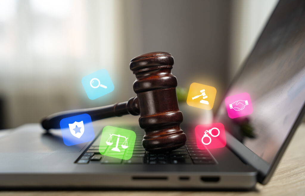 Legal symbols float around a gavel that is resting on the keyboard of a laptop.