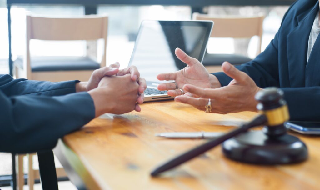 An attorney sits across from a client at a desk talking.