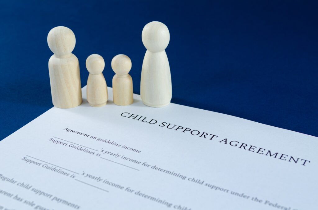 Four wooden figures depicting a family rest on a child support agreement.