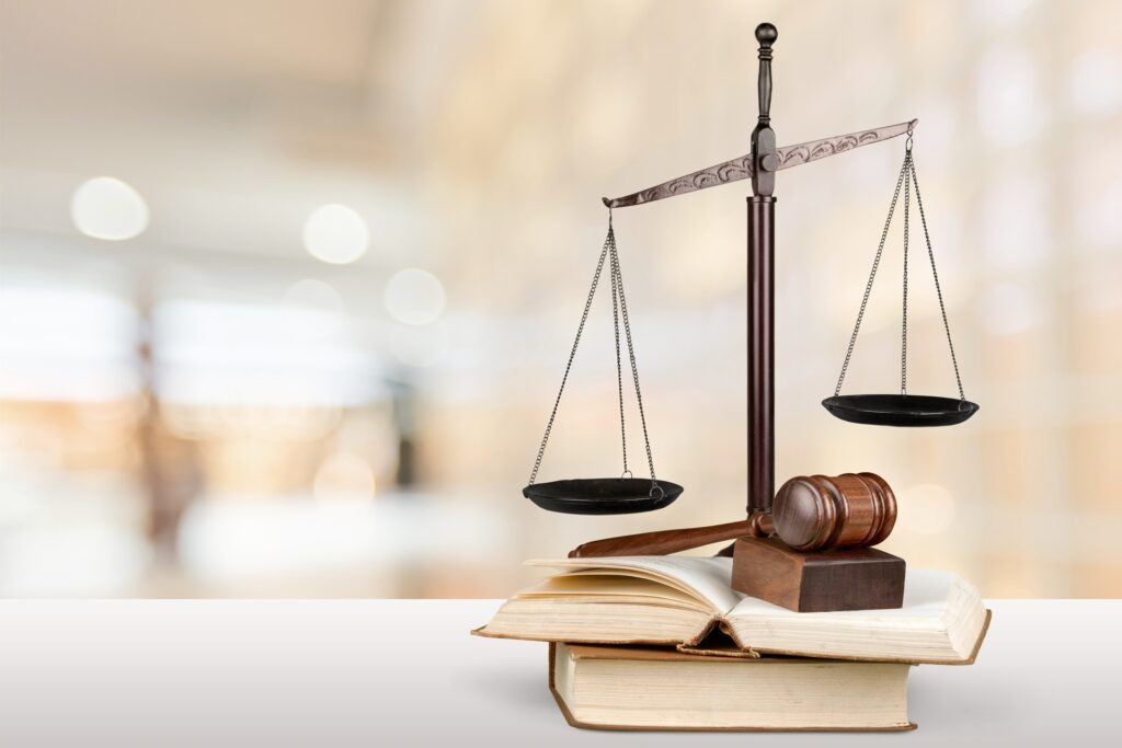 A gavel rests on its stand on top of two law books in front of scales of justice.