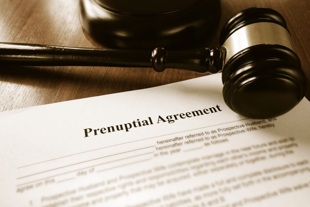 A prenuptial agreement sits on a wooden desk resting under a gavel.