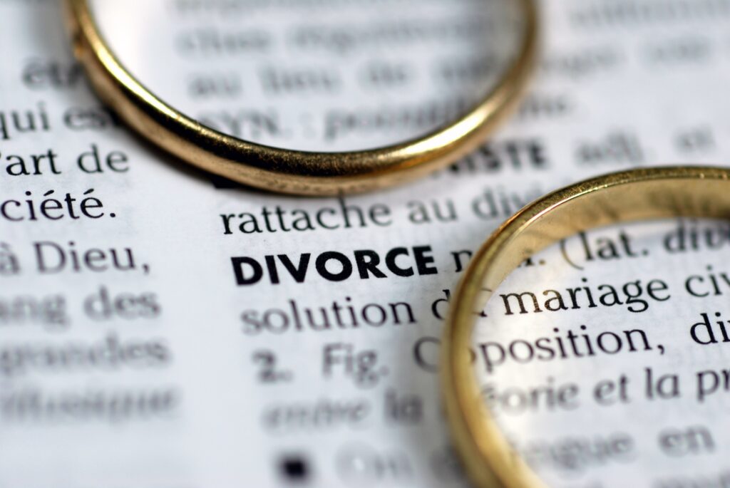 Two gold wedding rings sit on a dictionary next to the description of the word divorce.