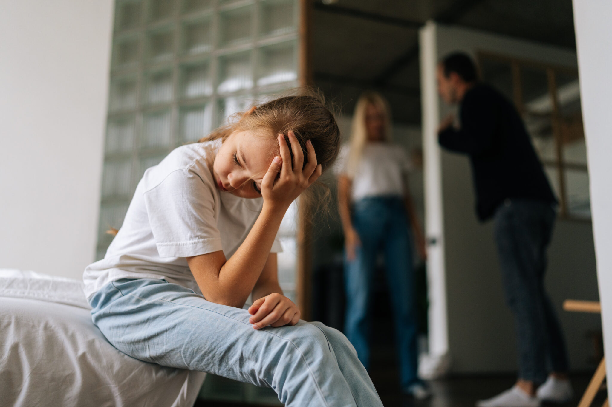 Upset child sitting apart while parents argue in background | Hemmat Law Group