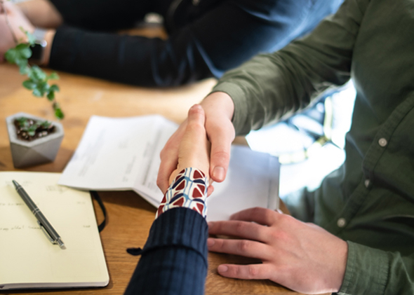 Two professionals shaking hands across an office meeting table | Hemmat Law Group