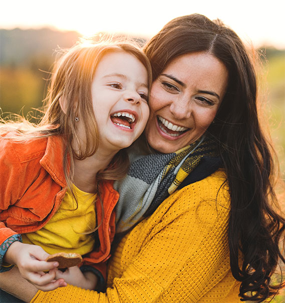 Smiling mother and daughter sharing a warm moment outdoors | Hemmat Law Group
