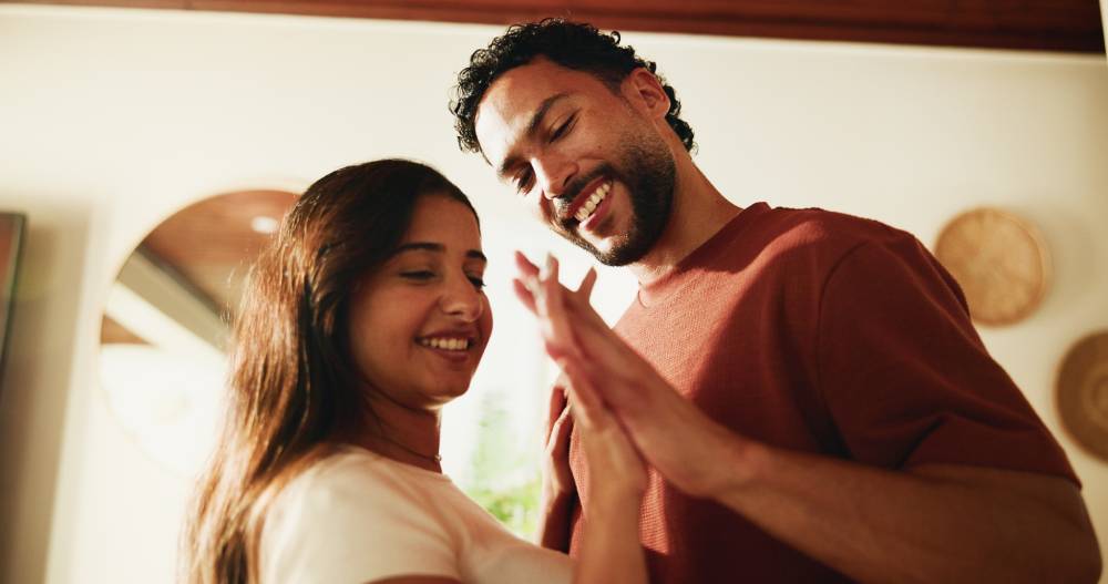 Happy couple smiling together while holding up their hands | Hemmat Law Group