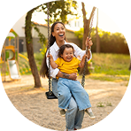 Mother pushing her smiling child on a playground swing | Hemmat Law Group