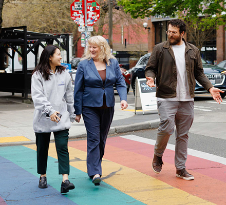 Three people walking together across a colorful city crosswalk | Hemmat Law Group