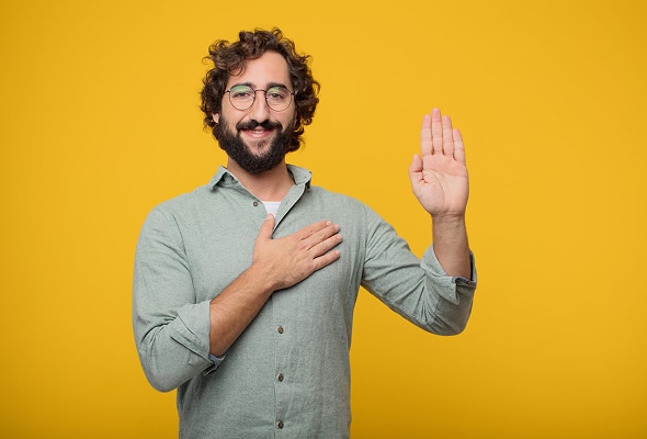 Smiling man raising one hand as if taking a formal oath | Hemmat Law Group