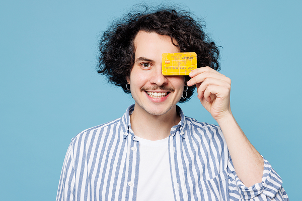 Smiling man holding up a credit card against blue background | Hemmat Law Group