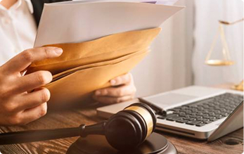 Legal professional reviewing documents beside gavel and laptop | Hemmat Law Group