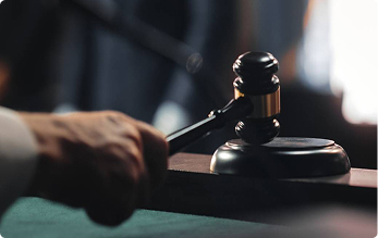 Judge raising a wooden gavel above the courtroom bench | Hemmat Law Group