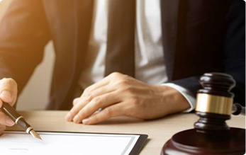 Legal professional signing documents beside a wooden gavel | Hemmat Law Group