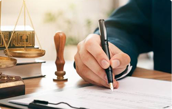 Legal professional signing a document beside scales of justice | Hemmat Law Group