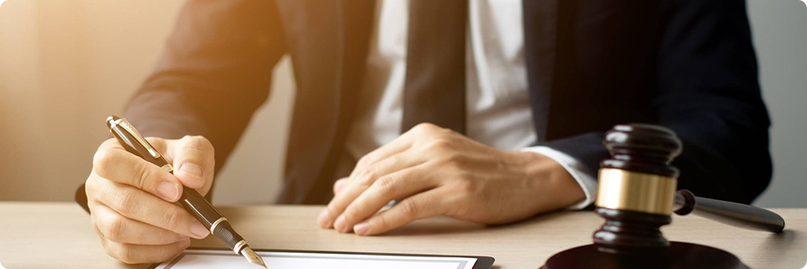 Legal professional signing documents beside a judge's gavel | Hemmat Law Group