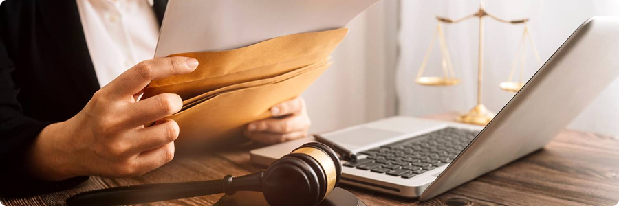 Legal professional reviewing documents beside laptop and gavel | Hemmat Law Group