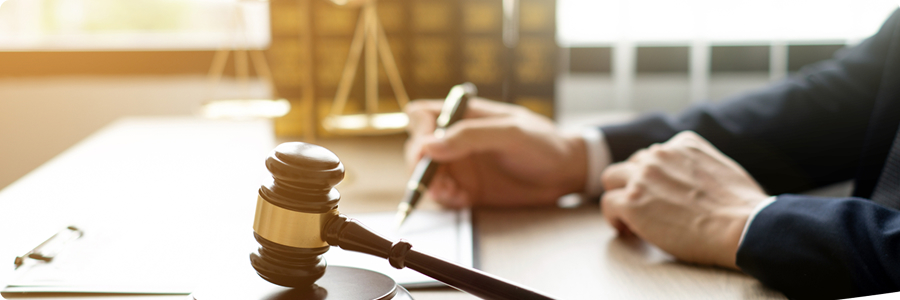 Legal professional signing a document beside a judge's gavel | Hemmat Law Group
