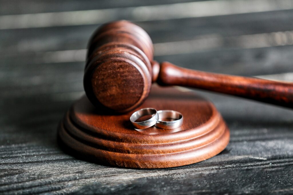 Wedding rings resting beside a wooden judge's gavel | Hemmat Law Group