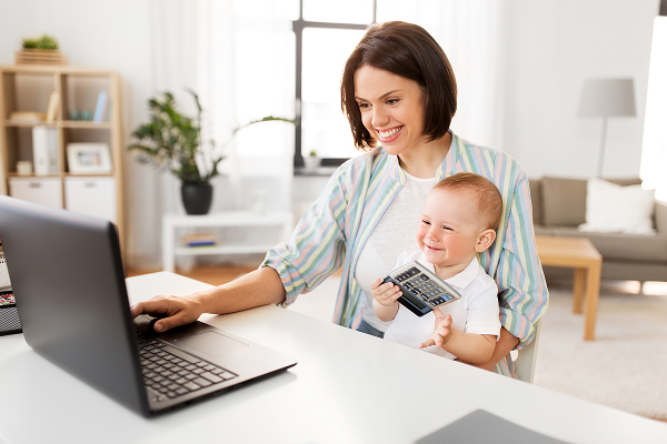 Mother working on laptop holding smiling baby | Hemmat Law Group