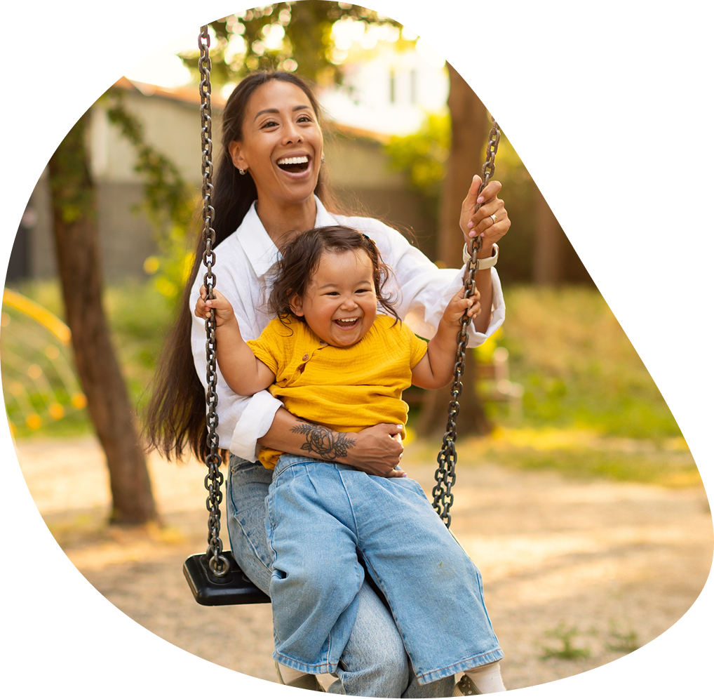 Laughing mother and toddler riding a park swing | Hemmat Law Group
