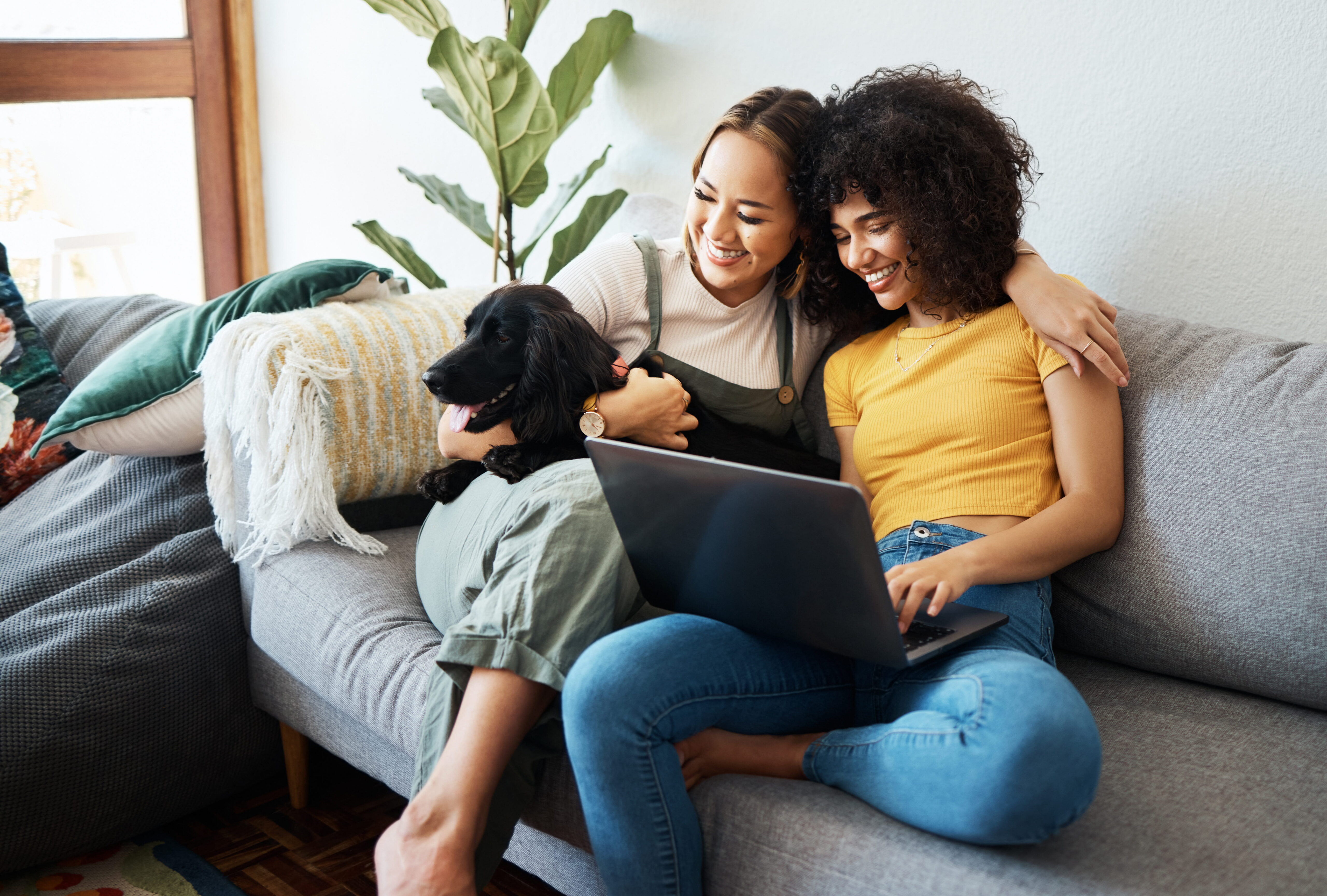 Same-sex couple relaxing with their dog and laptop at home | Hemmat Law Group