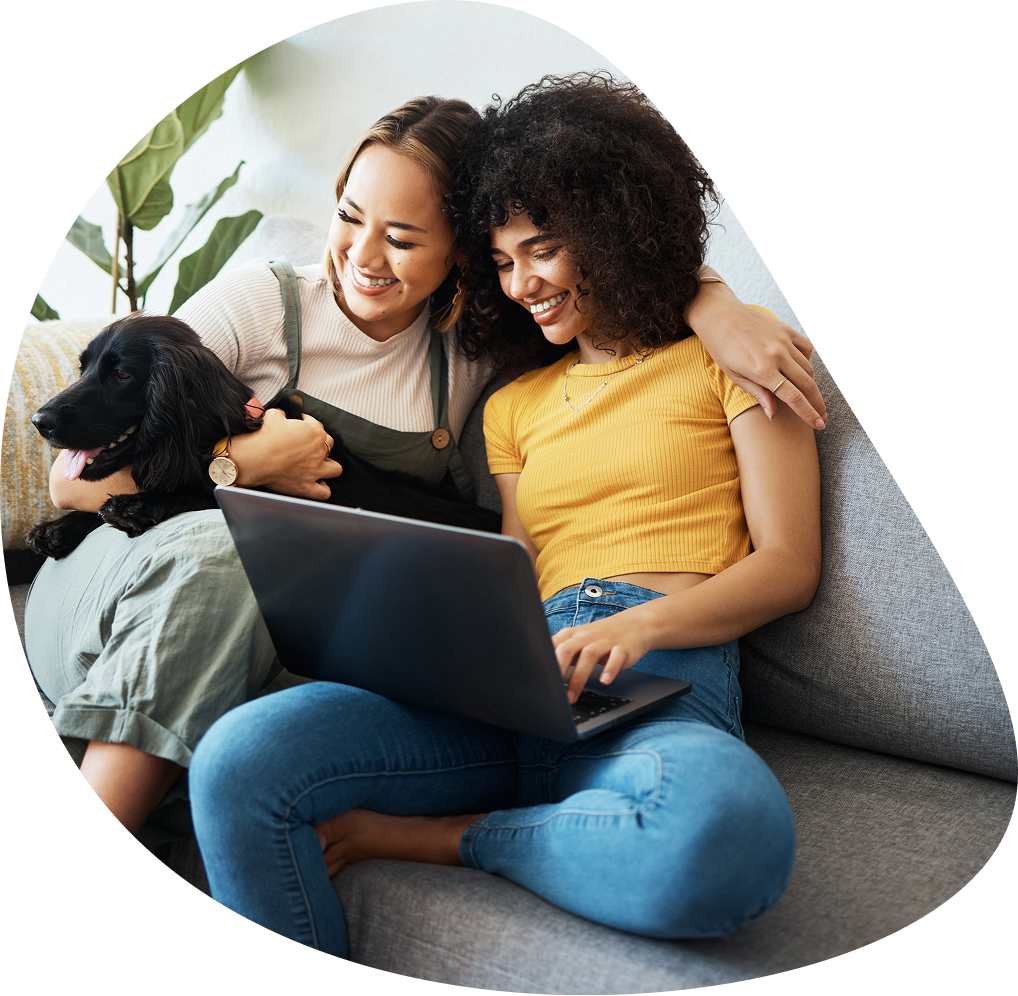 Two women with dog browsing laptop on couch | Hemmat Law Group