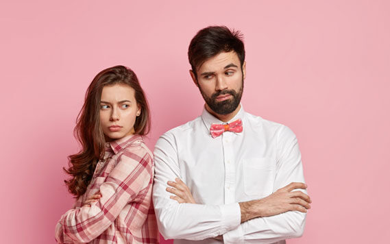 Unhappy couple standing apart against a pink background | Hemmat Law Group