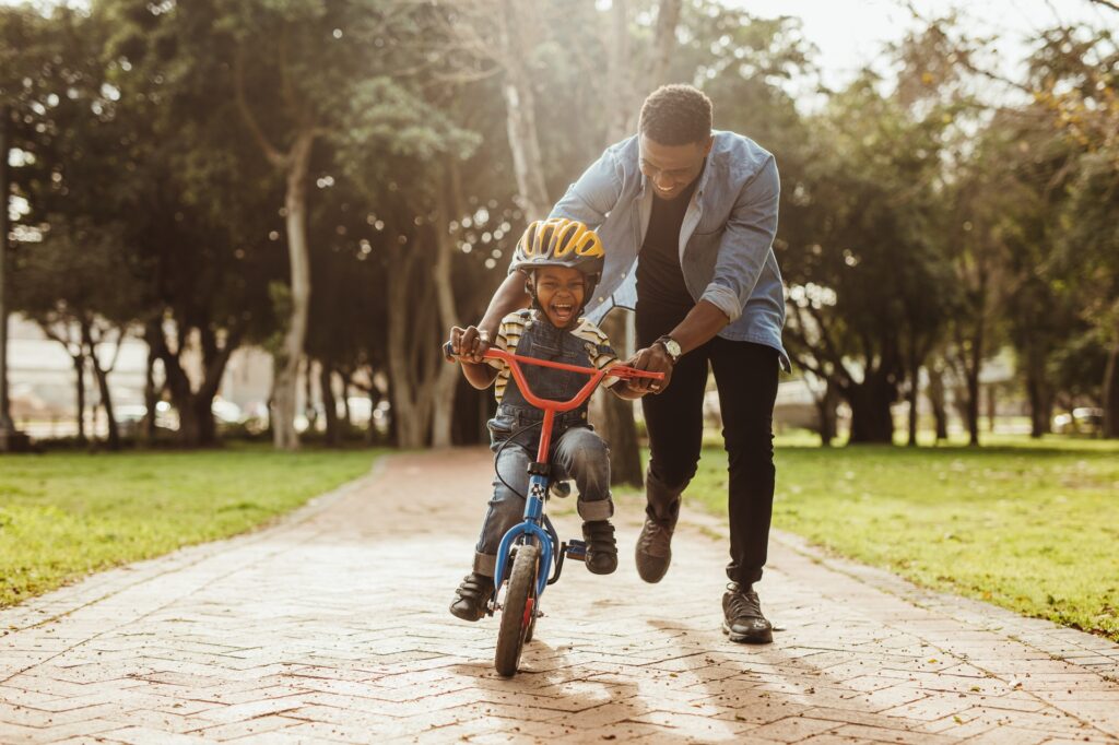 Father teaching son to ride a bicycle | Hemmat Law Group
