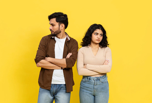 Upset couple standing apart with crossed arms on yellow | Hemmat Law Group