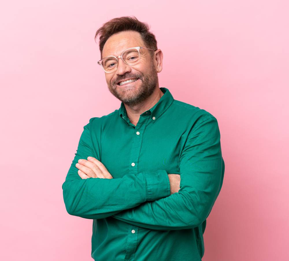 Smiling man in green shirt posing against pink background | Hemmat Law Group