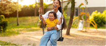 Mother pushing her laughing child on a playground swing | Hemmat Law Group
