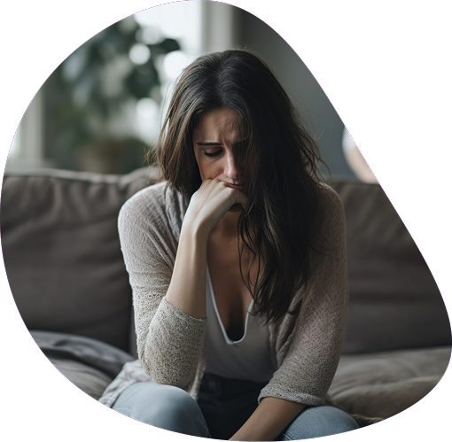 Distressed woman sitting alone on a sofa with her head down | Hemmat Law Group